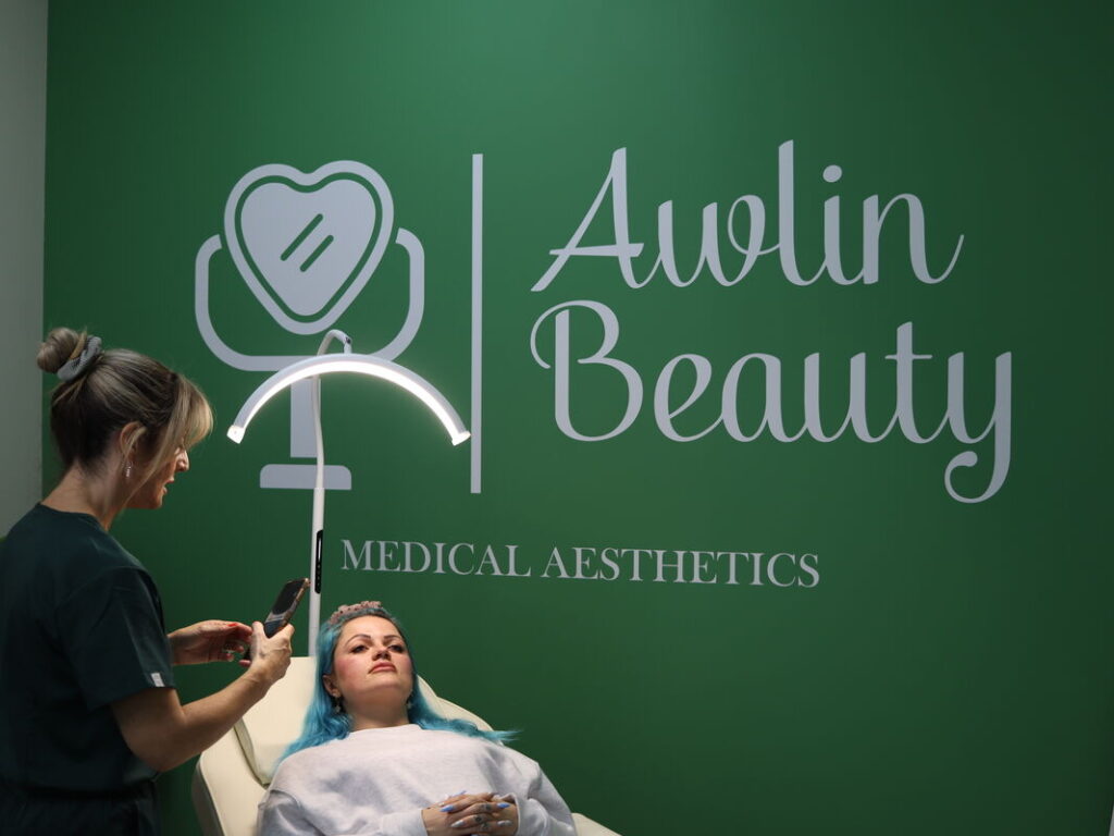 Practitioner consulting with a client in Awlin Beauty Medical Aesthetics clinic beneath the brand feature wall in Maidstone